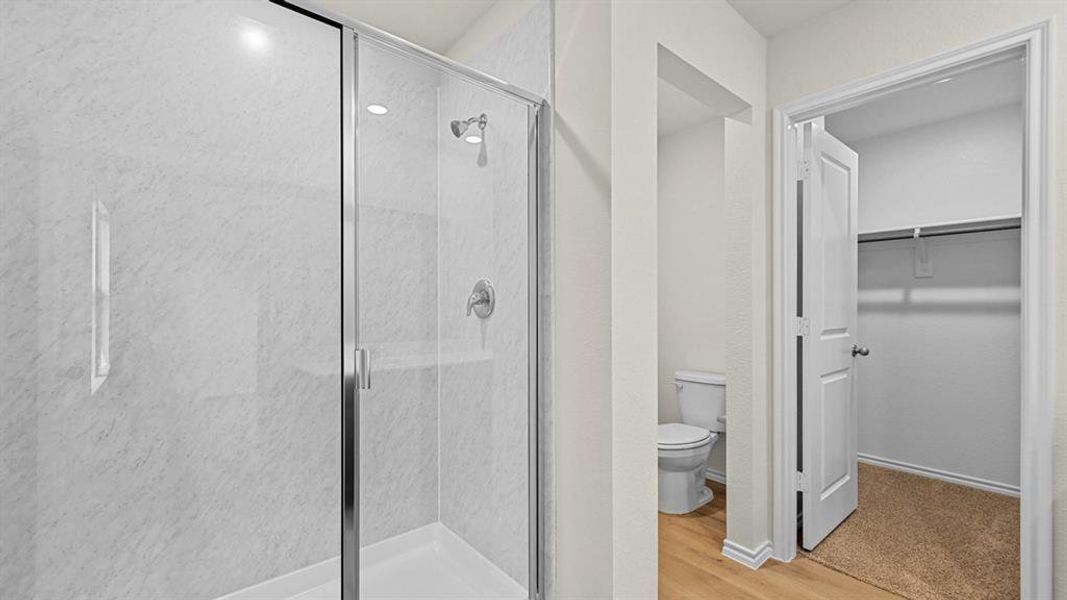 Bathroom with a stall shower, a walk in closet, and light wood finished floors