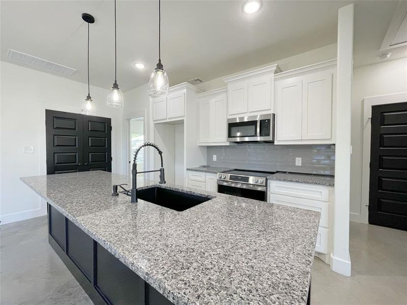 Kitchen with white cabinets, a kitchen island with sink, and stainless steel appliances