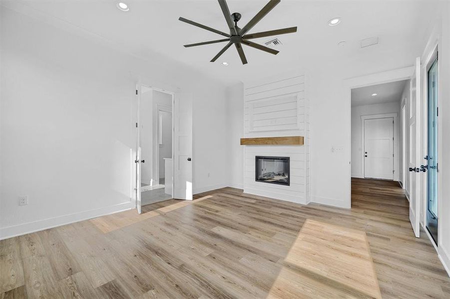 Unfurnished living room featuring a fireplace, light hardwood / wood-style flooring, and ceiling fan