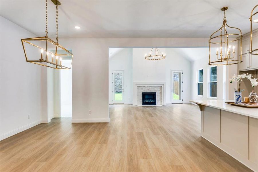 Unfurnished living room featuring a chandelier, a stone fireplace, light wood-style flooring, recessed lighting, and lofted ceiling Unfurnished living room featuring a chandelier, a stone fireplace, light wood-style flooring, recessed lighting, and lofted ceiling