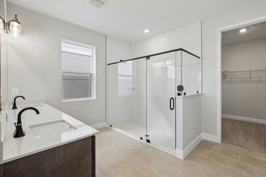 The primary bathroom has a large frameless walk-in shower