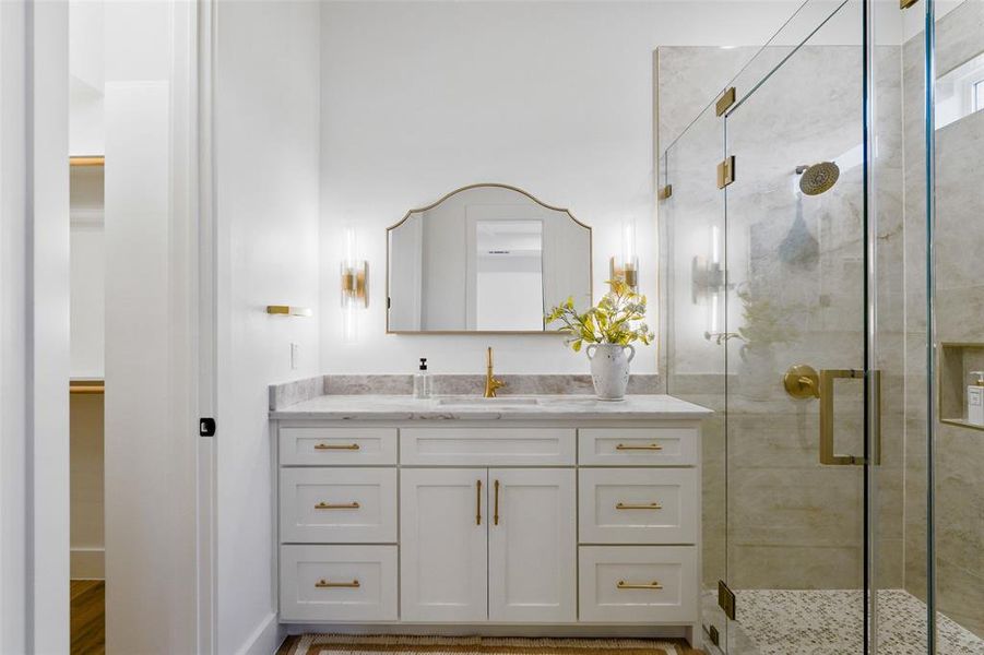 White vanity with gold hardware, a marble-finish countertop, and an undermount sink