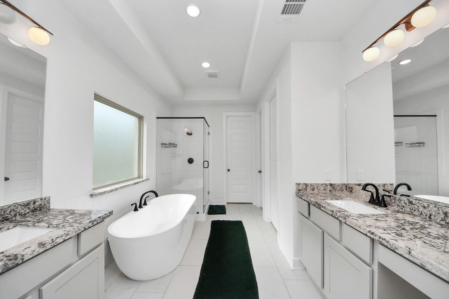 This bathroom features a modern design with a freestanding tub, glass-enclosed shower, and dual granite-topped vanities. Bright and spacious, it has sleek fixtures and ample natural light. This bathroom features a modern design with a freestanding tub, glass-enclosed shower, and dual granite-topped vanities. Bright and spacious, it has sleek fixtures and ample natural light.