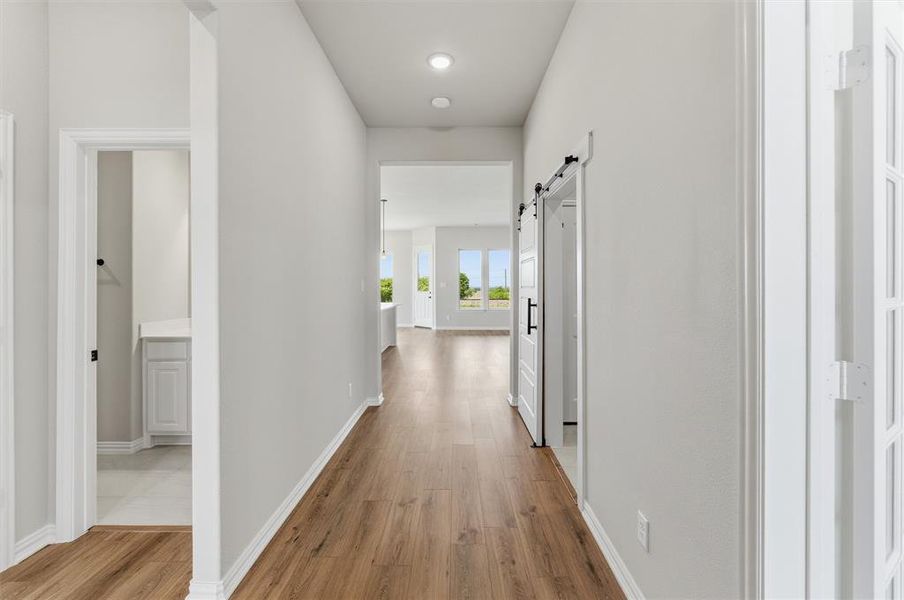 Hallway featuring a barn door and light wood-style floors Hallway featuring a barn door and light wood-style floors