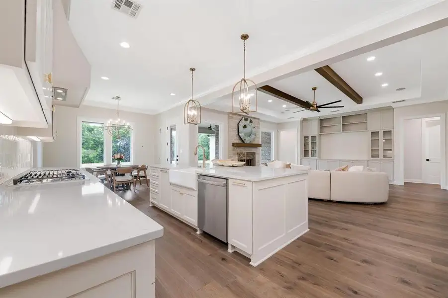 Kitchen featuring a ceiling fan, a stone fireplace, dark wood-style flooring, white cabinets, and open floor plan Kitchen featuring a ceiling fan, a stone fireplace, dark wood-style flooring, white cabinets, and open floor plan