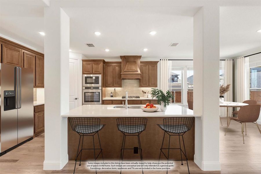 Kitchen with wood cabinets, large island with bar seating, stainless steel appliances, and custom range hood