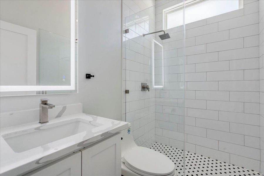 Bathroom featuring a tiled walk in shower and vanity
