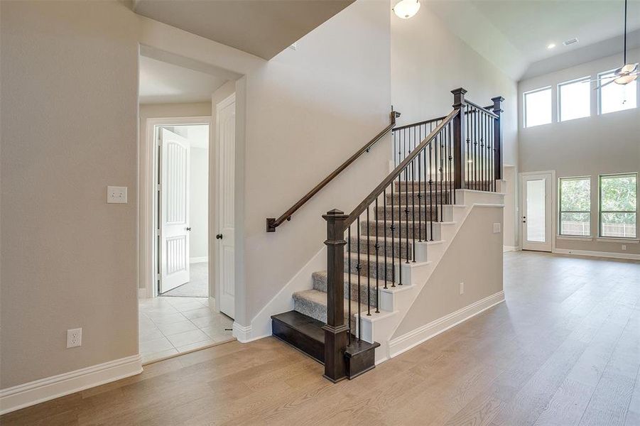 Staircase with hardwood / wood-style flooring and a towering ceiling