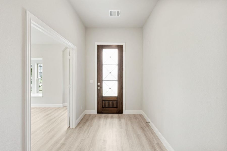 Entryway hallway with dark wood front door, glass panels, and light hardwood floors Entryway hallway with dark wood front door, glass panels, and light hardwood floors