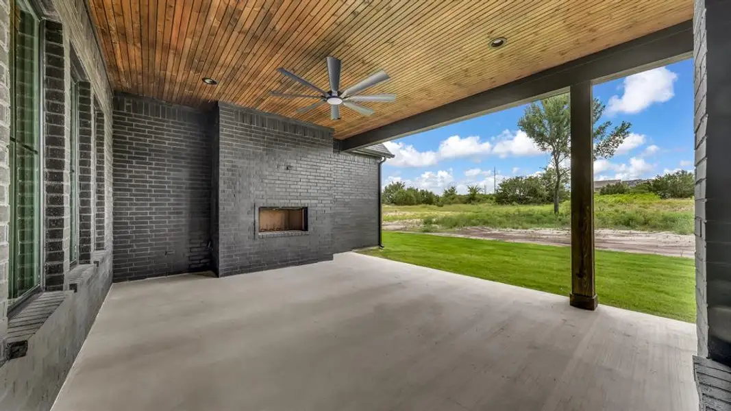 Covered patio with a wood-finish ceiling, built-in fireplace, and a ceiling fan