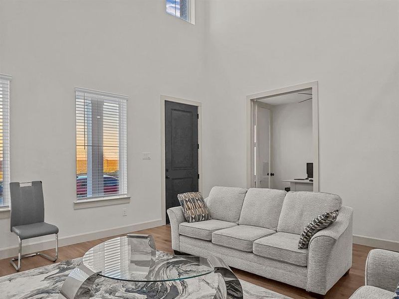 Living room with a towering ceiling and hardwood / wood-style flooring