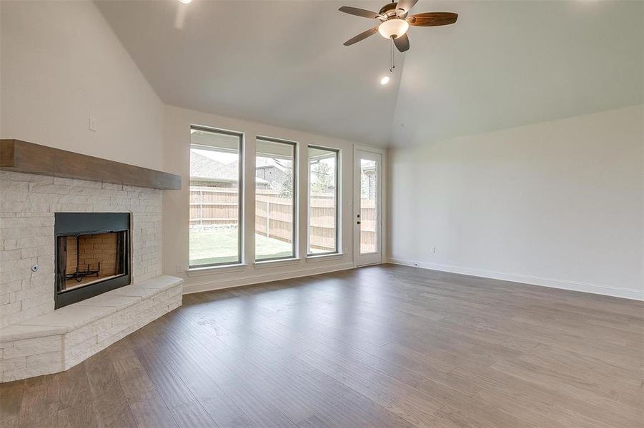 Unfurnished living room with high vaulted ceiling, a brick fireplace, hardwood / wood-style floors, and ceiling fan