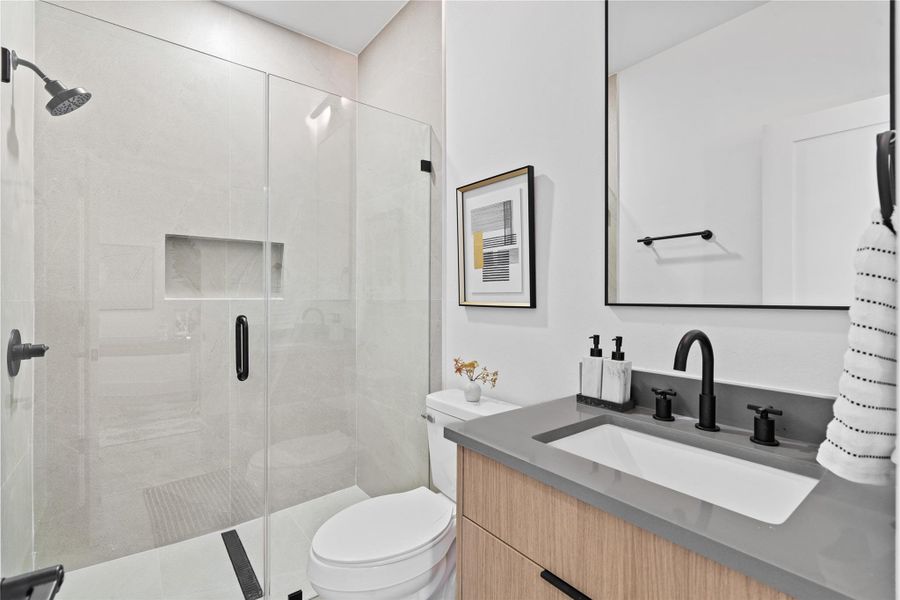 A serene and warm ensuite with a frameless glass shower with tiling to the ceiling and quartz countertops. A serene and warm ensuite with a frameless glass shower with tiling to the ceiling and quartz countertops.