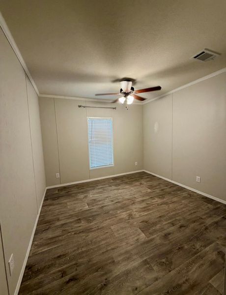 Spacious room featuring wood-finish flooring, neutral-toned walls, a window with blinds, and a ceiling fan with integrated lighting