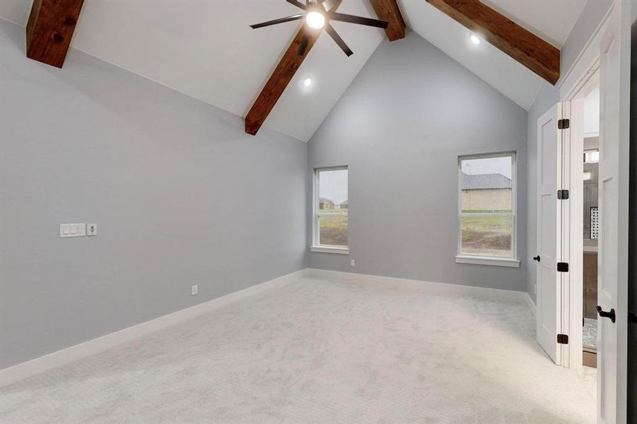 Empty room with beamed ceiling, light colored carpet, and plenty of natural light