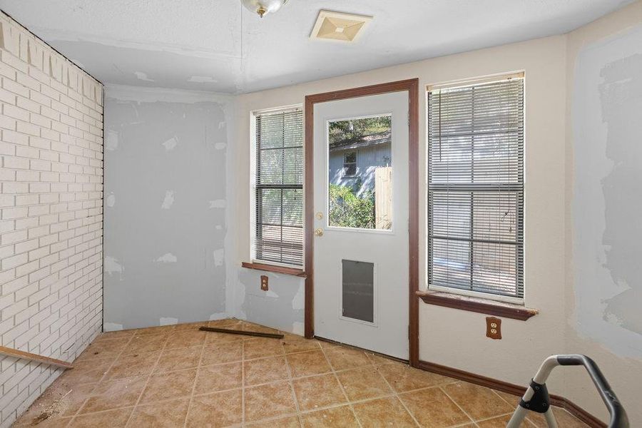 Enclosed back porch-Doorway with brick wall and tile patterned flooring