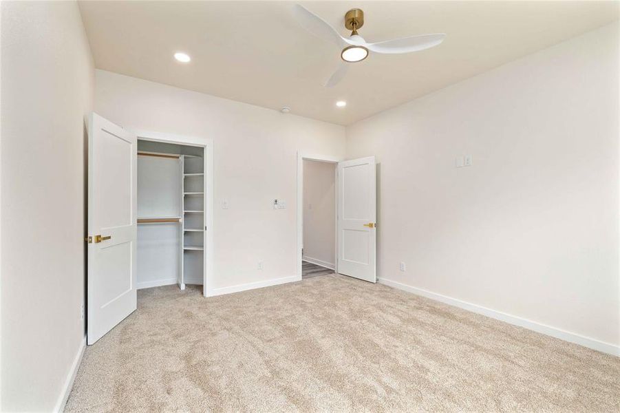 Unfurnished bedroom with light carpet, a walk in closet, a ceiling fan, and recessed lighting Unfurnished bedroom with light carpet, a walk in closet, a ceiling fan, and recessed lighting