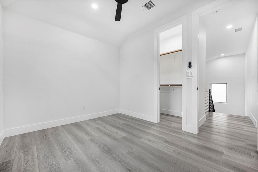 Unfurnished bedroom featuring recessed lighting, baseboards, wood-finished floors, a walk-in closet, and a ceiling fan. Unfurnished bedroom featuring recessed lighting, baseboards, wood-finished floors, a walk-in closet, and a ceiling fan.