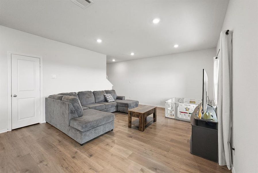 Living area featuring wood-finish flooring, recessed lighting, and white trim