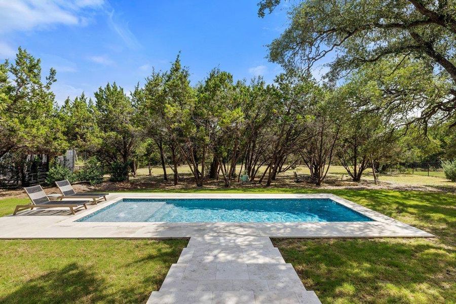 A private backyard oasis showcases a pristine inground pool surrounded by mature trees and lush green landscaping. A private backyard oasis showcases a pristine inground pool surrounded by mature trees and lush green landscaping.
