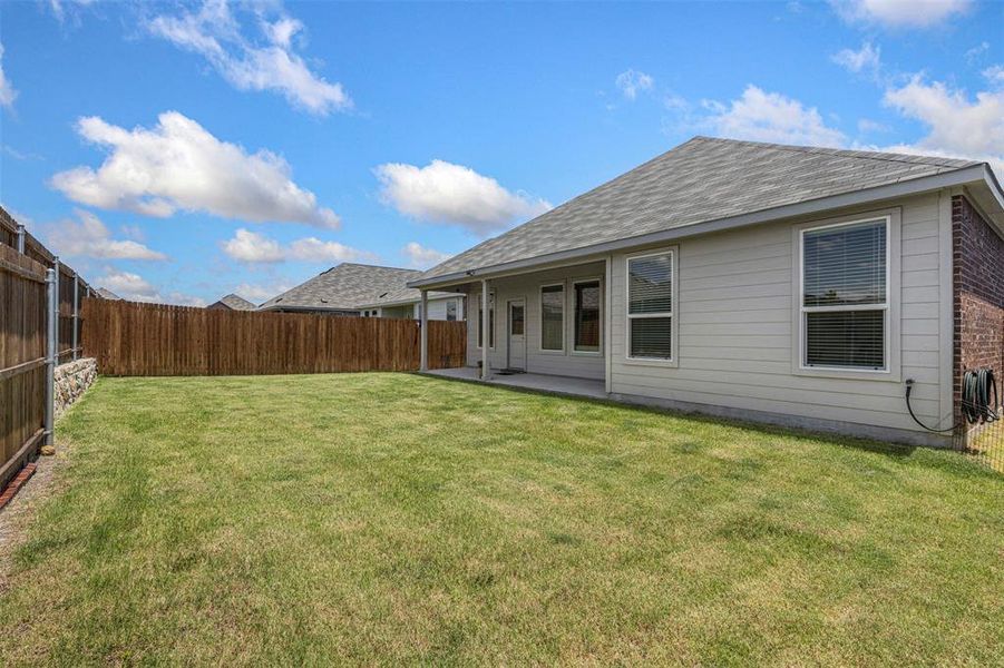 Expansive backyard featuring a manicured lawn, full privacy fencing, and a concrete patio Expansive backyard featuring a manicured lawn, full privacy fencing, and a concrete patio