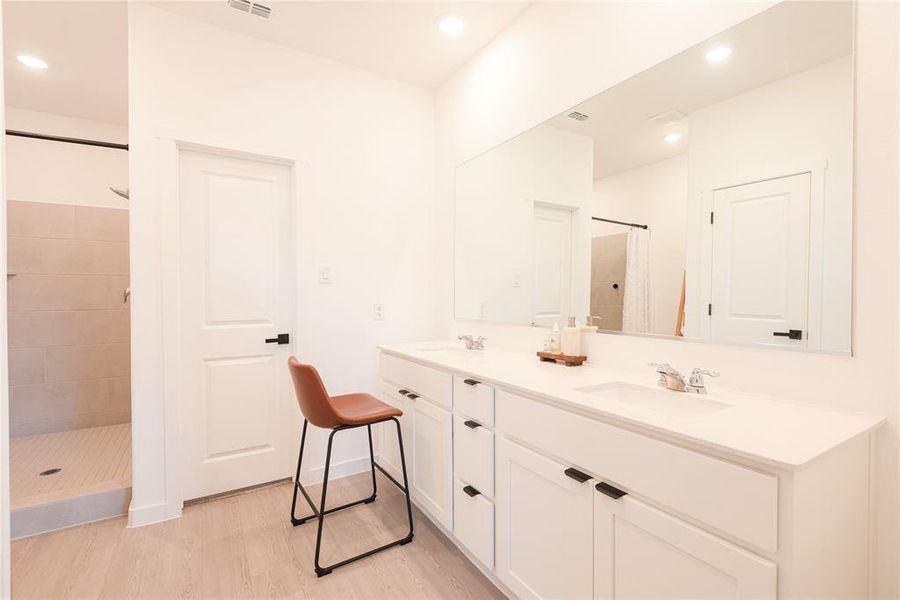 Bathroom featuring a stall shower, double vanity, light wood-style floors, and recessed lighting Bathroom featuring a stall shower, double vanity, light wood-style floors, and recessed lighting