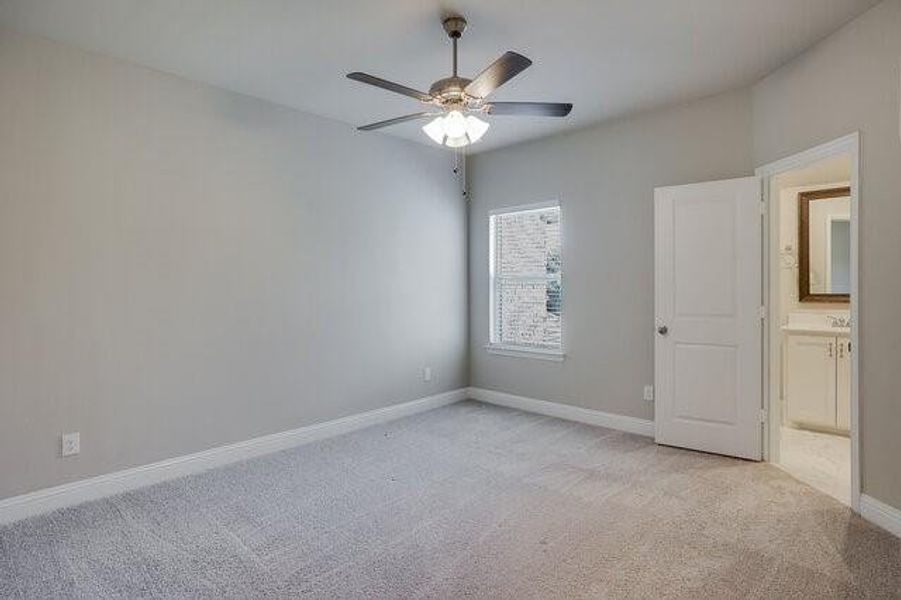 Spare room featuring light colored carpet, a ceiling fan, and baseboards