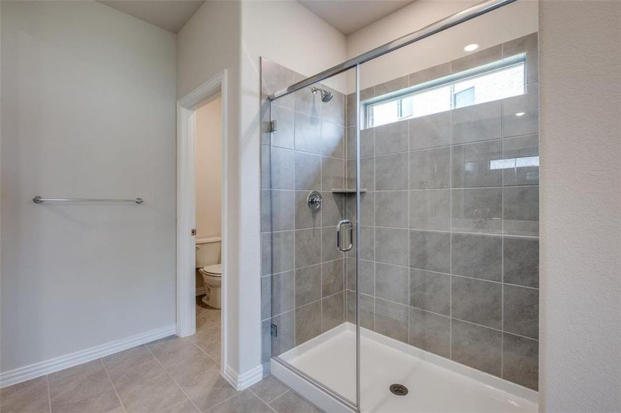 Bathroom featuring walk in shower, toilet, and tile patterned floors