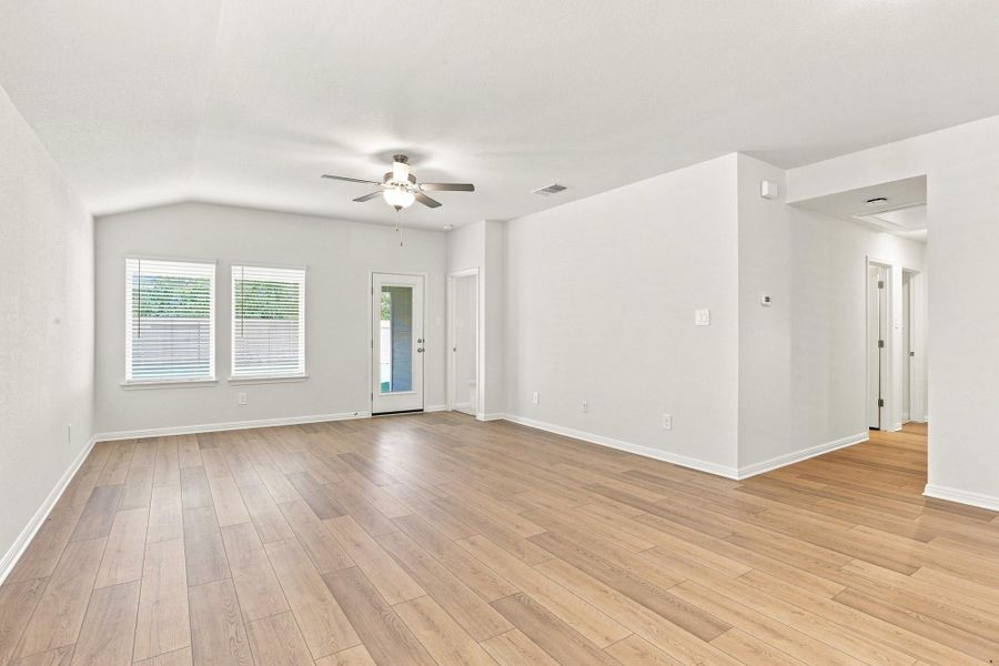 Warm wood flooring grounds this airy, light-filled living area featuring vaulted ceilings.
