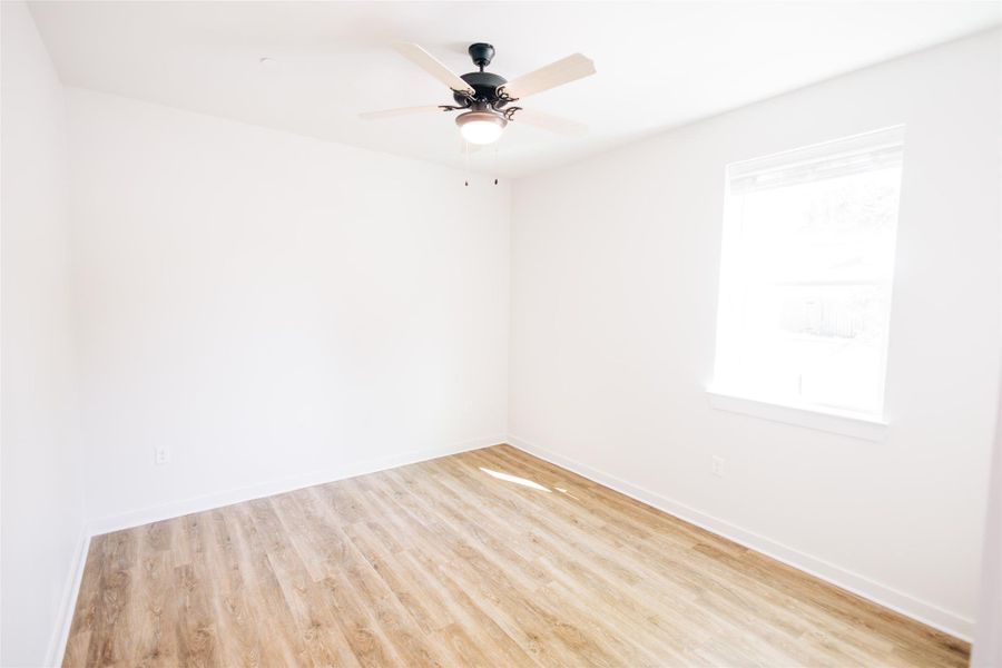 Empty room featuring wood finished floors, baseboards, and ceiling fan