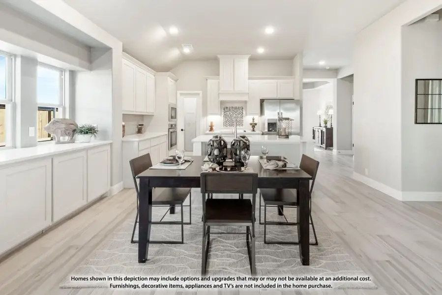 Open dining area with dark wood table flowing into white kitchen with island and light wood floors
