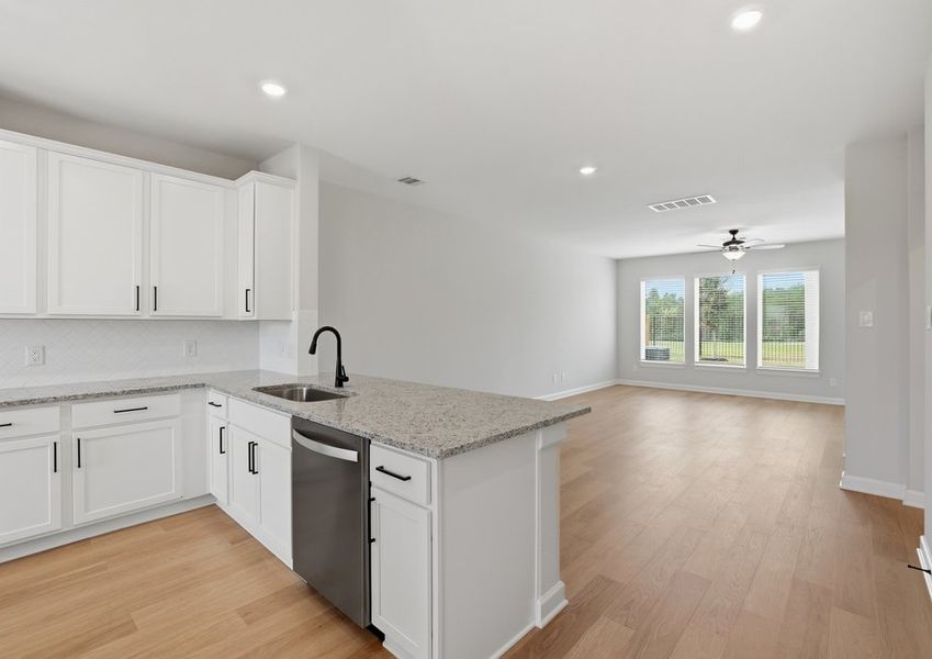 Kitchen featuring a granite island, white cabinetry, and a stainless dishwasher.