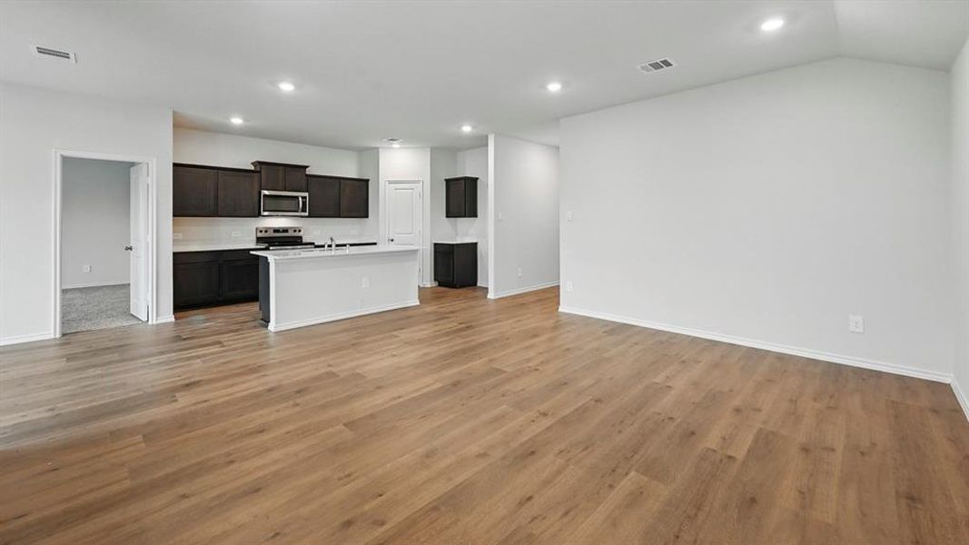 Kitchen featuring open floor plan, recessed lighting, an island with sink, appliances with stainless steel finishes, and light wood finished floors