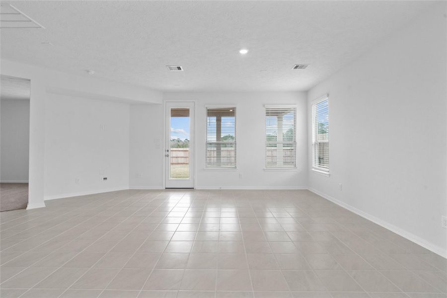 Gather the family and guests together in your lovely family room! Featuring high ceilings, recessed lighting, custom paint, gorgeous tile floors, large windows with blinds, and an access door to the covered patio and backyard.