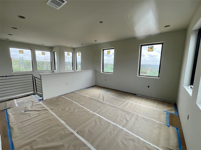 This open concept space features numerous windows providing abundant natural light and views, along with recessed lighting and a contemporary railing design