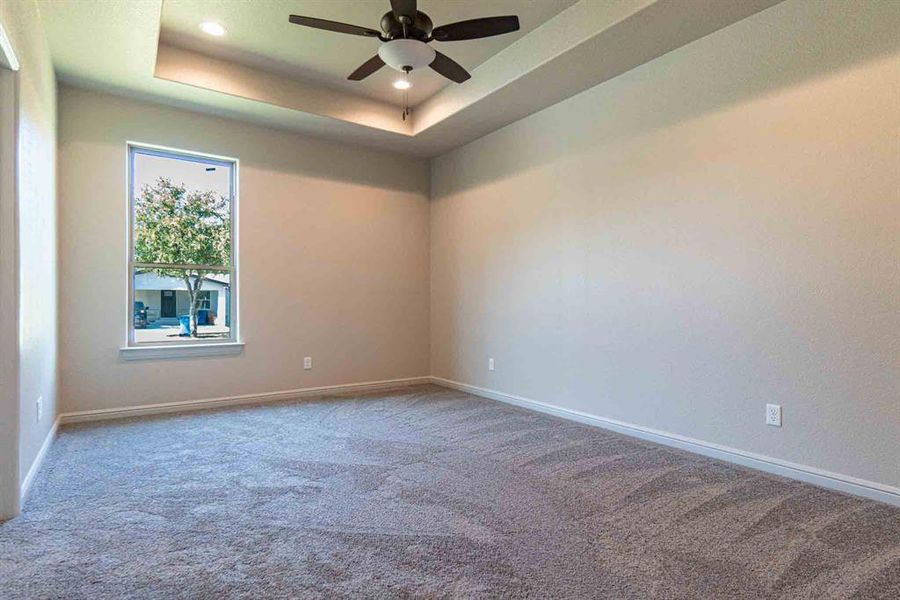 Carpeted spare room featuring a raised ceiling, recessed lighting, and ceiling fan