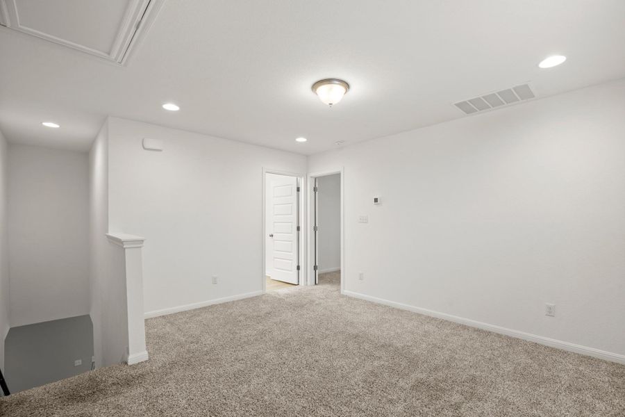 Empty room featuring light carpet, recessed lighting, and attic access