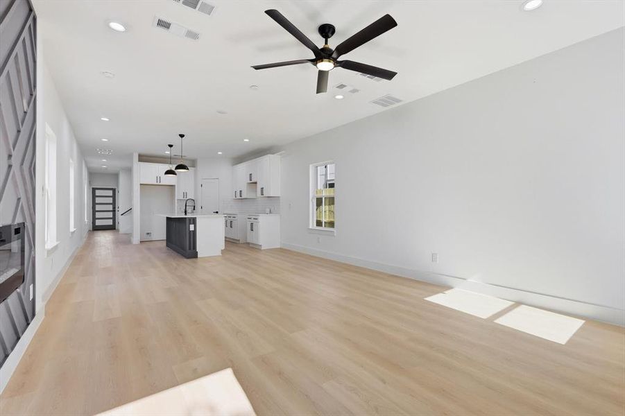 Unfurnished living room with ceiling fan, light wood-style flooring, recessed lighting, and stairs Unfurnished living room with ceiling fan, light wood-style flooring, recessed lighting, and stairs