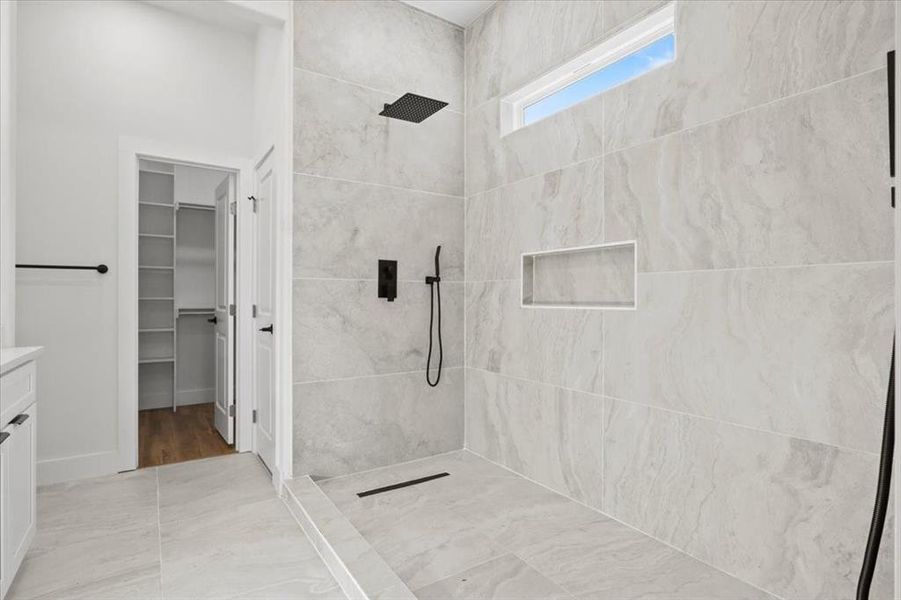 Full bathroom with vanity, a tile shower, and a walk in closet