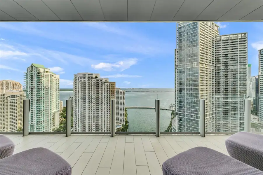 Covered balcony featuring oversized tile flooring and a transparent glass panel railing Covered balcony featuring oversized tile flooring and a transparent glass panel railing