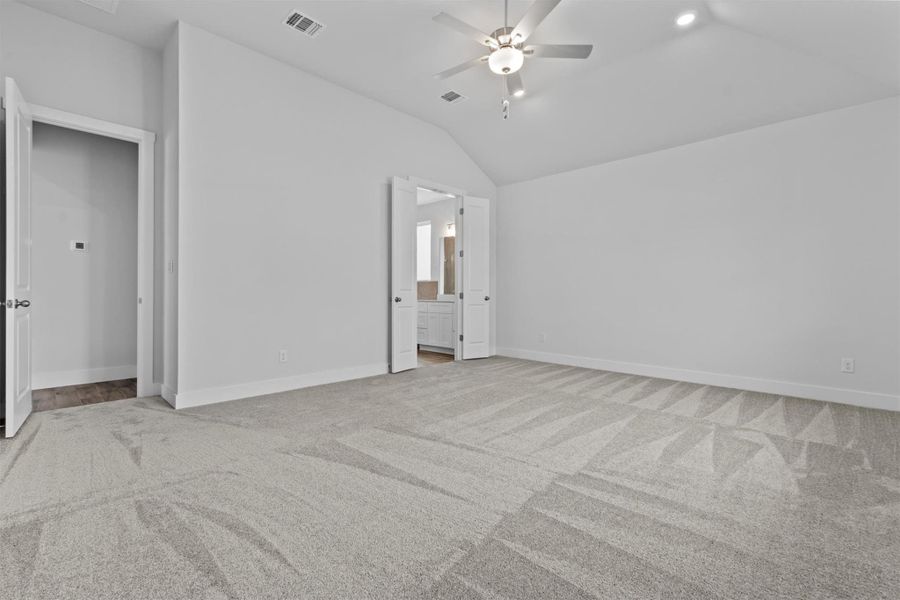 Unfurnished bedroom featuring ceiling fan, lofted ceiling, and carpet flooring