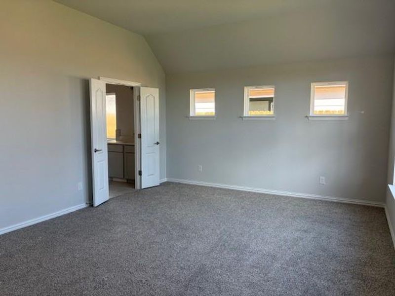 Unfurnished bedroom featuring vaulted ceiling, carpet, and ensuite bath Unfurnished bedroom featuring vaulted ceiling, carpet, and ensuite bath