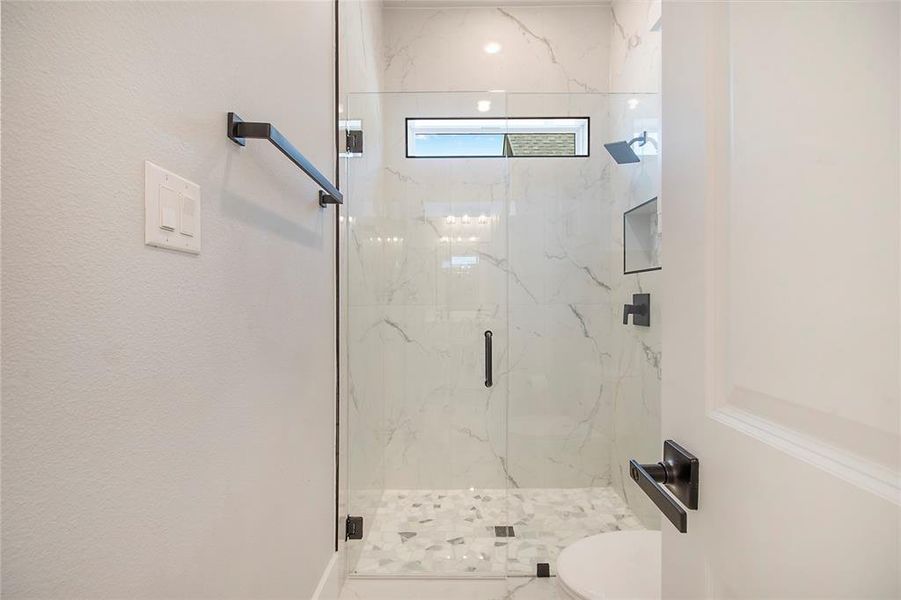 Full bathroom featuring a marble finish shower and toilet Full bathroom featuring a marble finish shower and toilet
