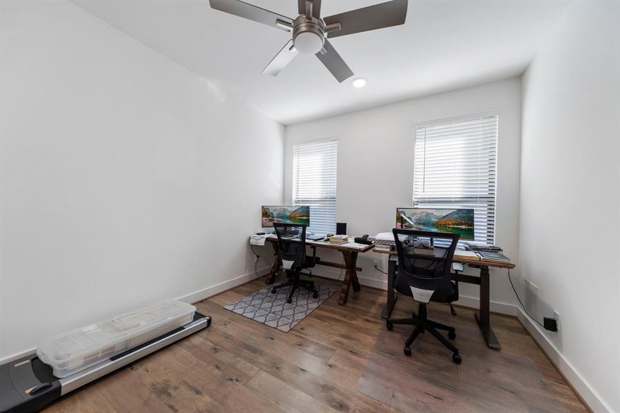 The secondary bedrooms showcase engineered wood flooring, a modern ceiling fan, and large windows that echo the home's cohesive design, offering a bright and inviting atmosphere.