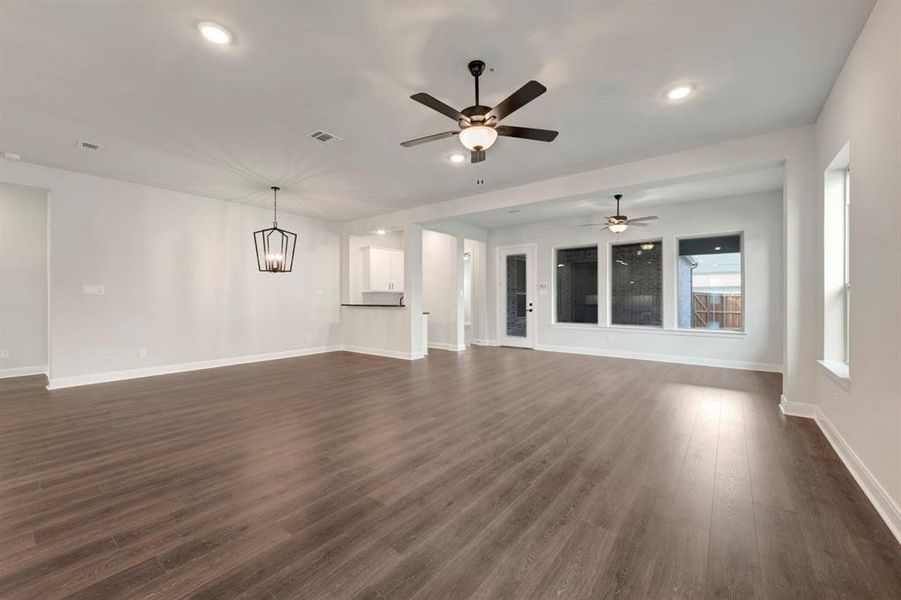 Unfurnished living room with dark wood finished floors, a ceiling fan, and hanging lights