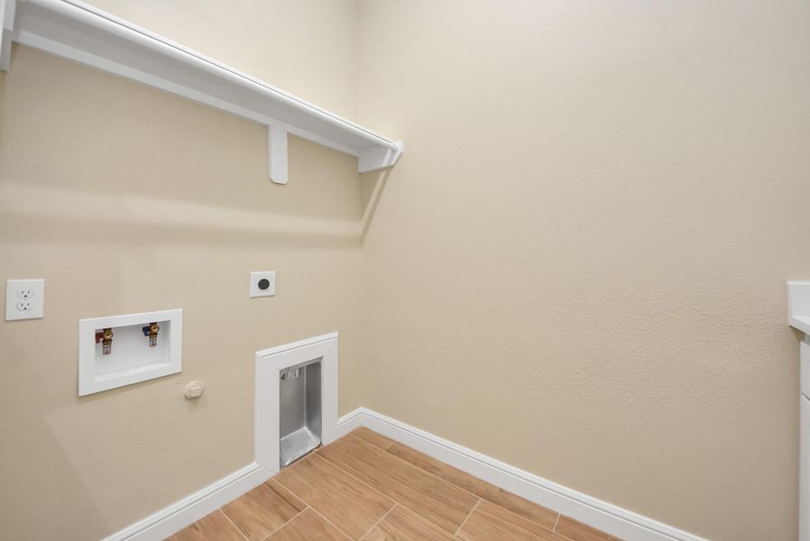 Here are the connections for a washer and dryer. It includes a shelf for storage and is equipped with necessary outlets and plumbing.