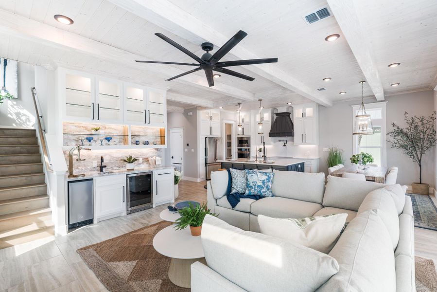 Living area with beverage cooler, recessed lighting, light wood-type flooring, bar with sink, and stairs Living area with beverage cooler, recessed lighting, light wood-type flooring, bar with sink, and stairs