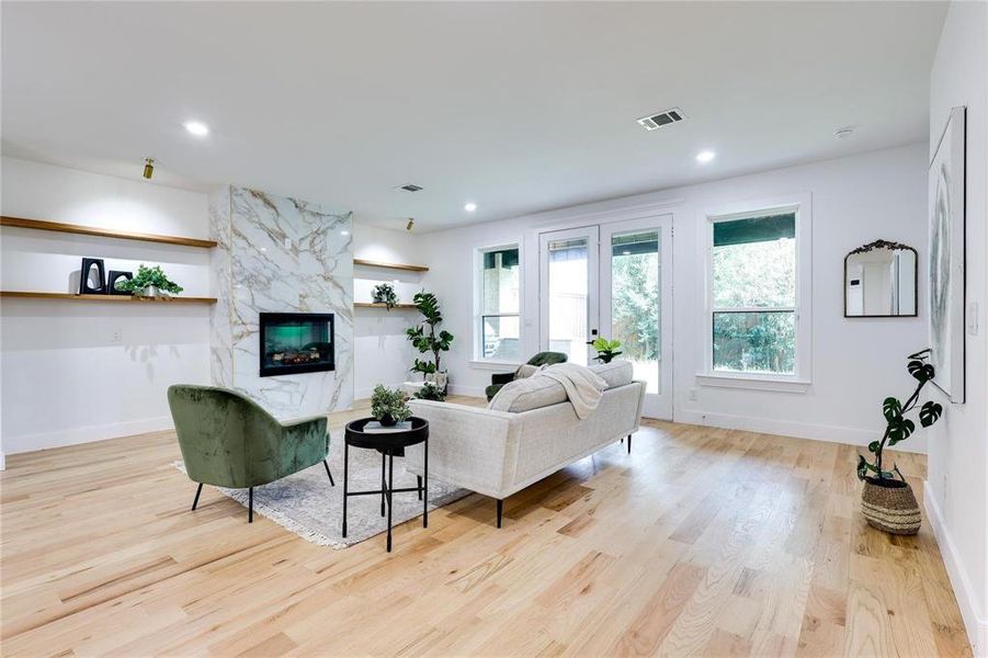 Living room featuring a premium fireplace, a wealth of natural light, and light hardwood / wood-style floors