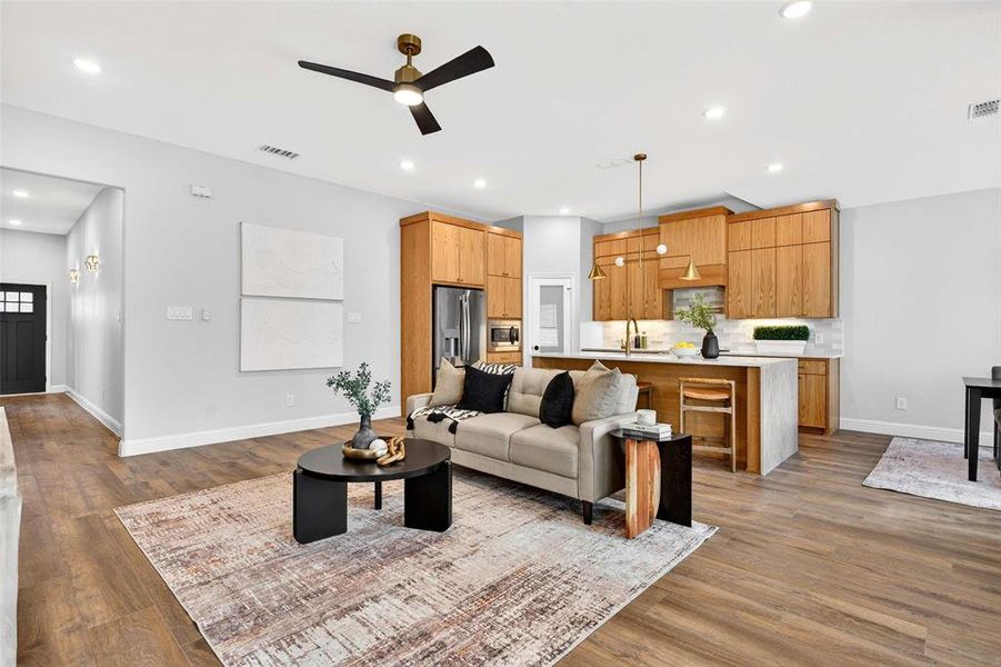Living room with ceiling fan, light wood-style flooring, and recessed lighting