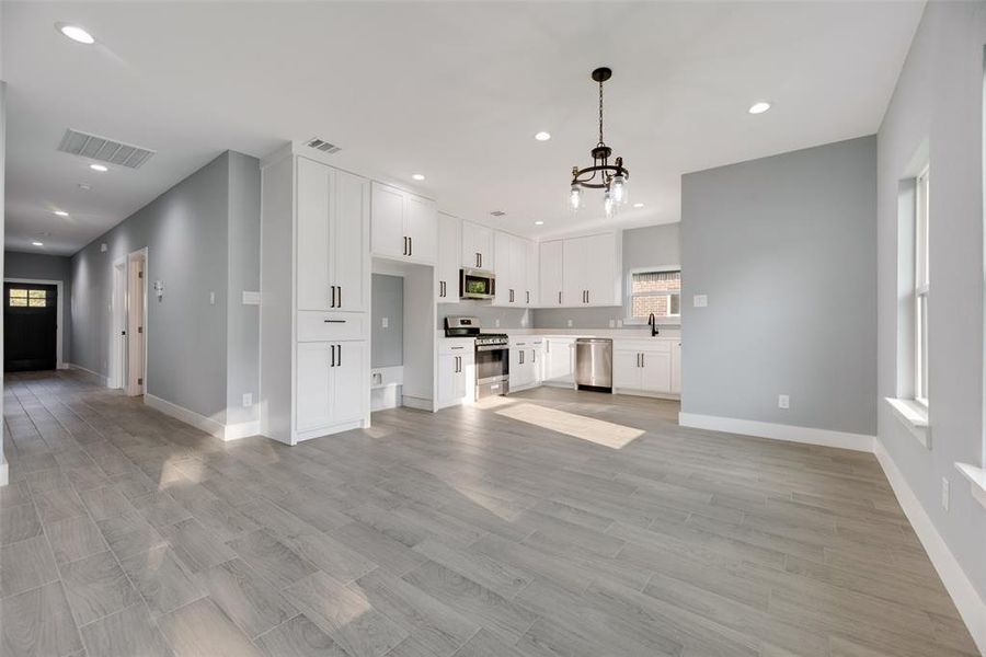 Unfurnished living room featuring light hardwood / wood-style floors, sink, and a chandelier